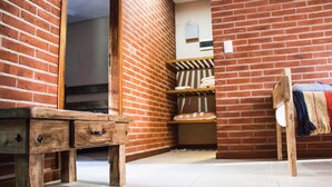 A corner room with a wooden bench, a small table, and a brick wall. - Agostina´s (Valeria del Mar)