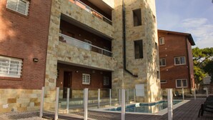 A multi-story building with a pool area, stone facade, and balconies. - Agostina´s (Valeria del Mar)