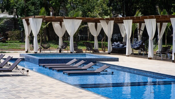 Une piscine dotée de chaises longues et d’une structure en forme de tonnelle.