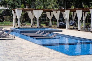 A swimming pool with lounge chairs and a canopy structure.