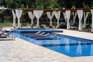 Piscina con sillas de descanso y una estructura tipo sombrilla.