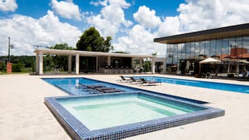 A swimming pool with lounge chairs and a covered area with tables and umbrellas.