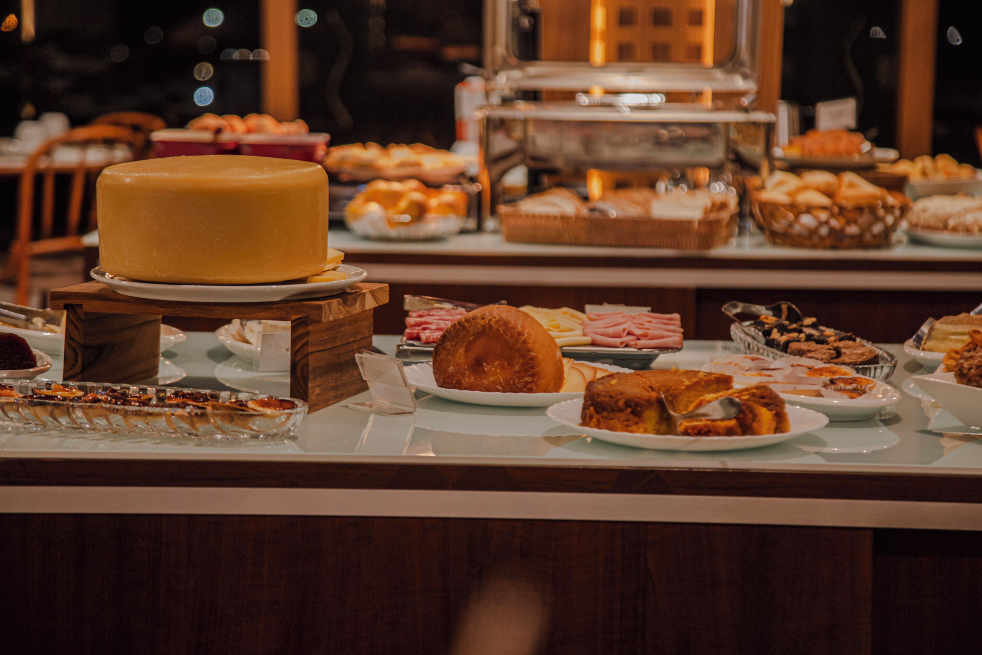 Un buffet proposant une variété de plats, notamment un grand plateau de fromages, des pâtisseries et d’autres mets.
