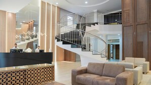 Un hall d’entrée spacieux, doté d’un escalier moderne, d’un comptoir de réception et de coins salons confortables.