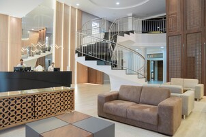 Un vestíbulo espacioso con una escalera moderna, un mostrador de recepción y cómodas zonas de estar.