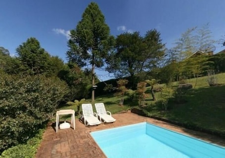 Una piscina al aire libre, sillones reclinables de piscina