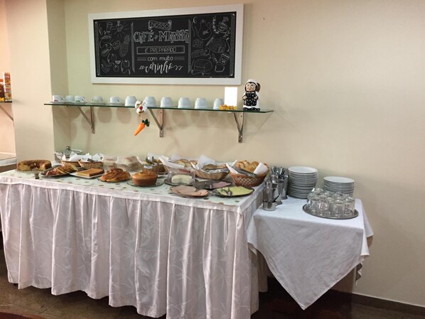 Een buffet met diverse etenswaren en bestek, een schoolbord erboven en een decoratief object aan de muur.