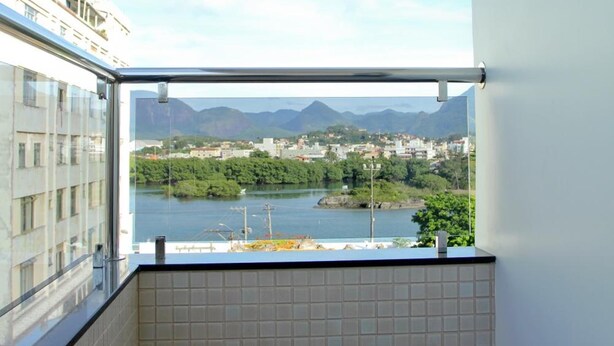 A balcony with a tiled floor and a view of a river and mountains. - Pousada Raio de Sol (Guarapari)