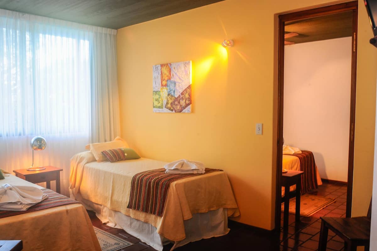 A hotel room with a bed, a bedside table, a lamp, and a painting on the wall.