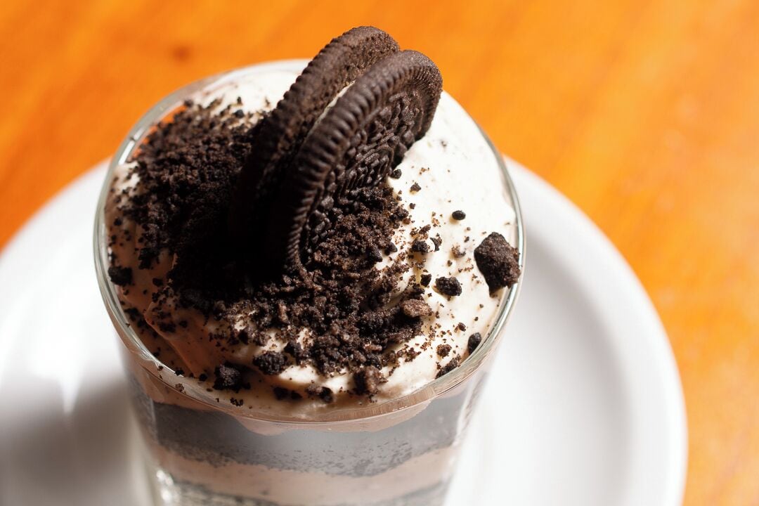 A dessert in a clear glass with a cookie on top.