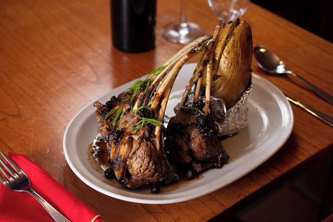 A plate of roasted lamb chops with a bone, served on a white plate.