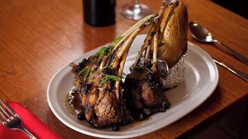 A plate of roasted lamb chops with a bone, served on a white plate.