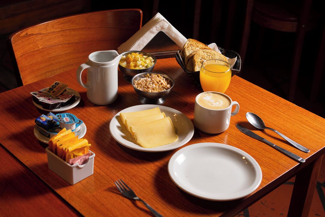 Une table de petit-déjeuner avec une variété d’aliments, notamment des céréales, du beurre et du jus d’orange.