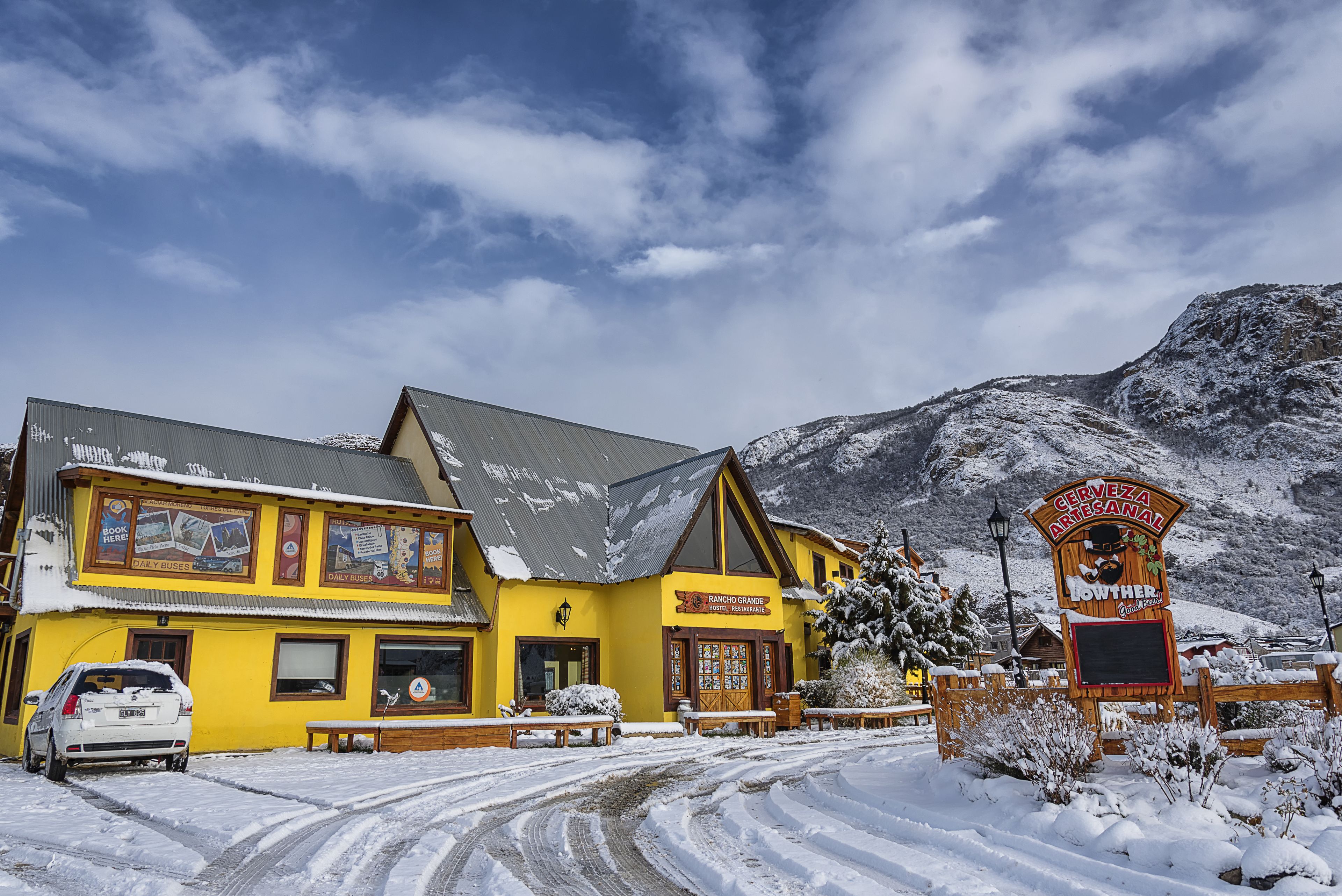 Een geel gebouw met een bord waarop staat 'Ranch Grande Post Office Restaurant' en een bord voor 'Cerveza Artesanal'.
