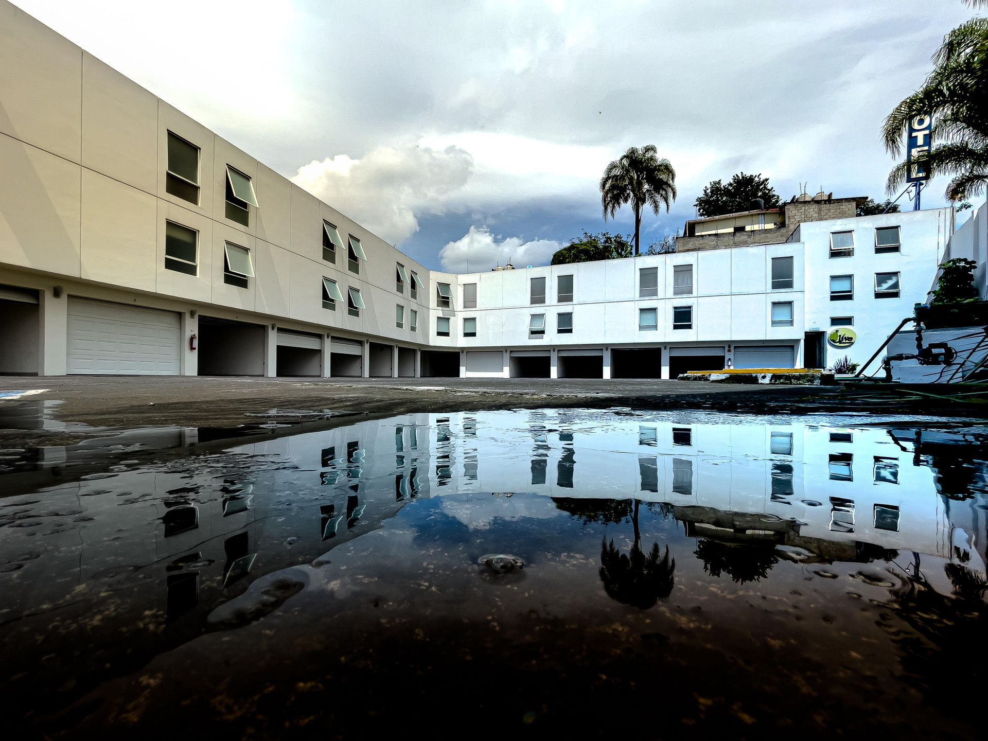 Un edificio de varios pisos, con numerosas ventanas y una superficie acuática reflectante al frente.