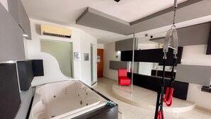 A modern bathroom with a large bathtub, a red chair, and a hanging exercise rope. - Auto-hotel Mediterraneo (Banderilla)
