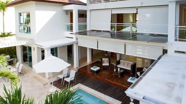 A modern two-story house with a swimming pool, outdoor seating, and a large balcony. - Villa Ibiza - Cocotal 3.5 Hab (Punta Cana)
