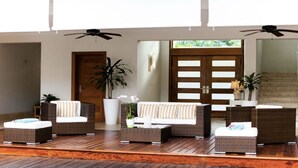 A spacious lobby with a wooden floor, a sofa set, two potted plants, and a large mirror reflecting the room. - Villa Ibiza - Cocotal 3.5 Hab (Punta Cana)