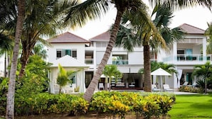 A two-story resort with a pool, palm trees, and a well-maintained lawn. - Villa Ibiza - Cocotal 3.5 Hab (Punta Cana)