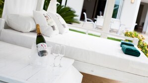 A white outdoor seating area with a bottle of champagne and glasses on a table. - Villa Ibiza - Cocotal 3.5 Hab (Punta Cana)