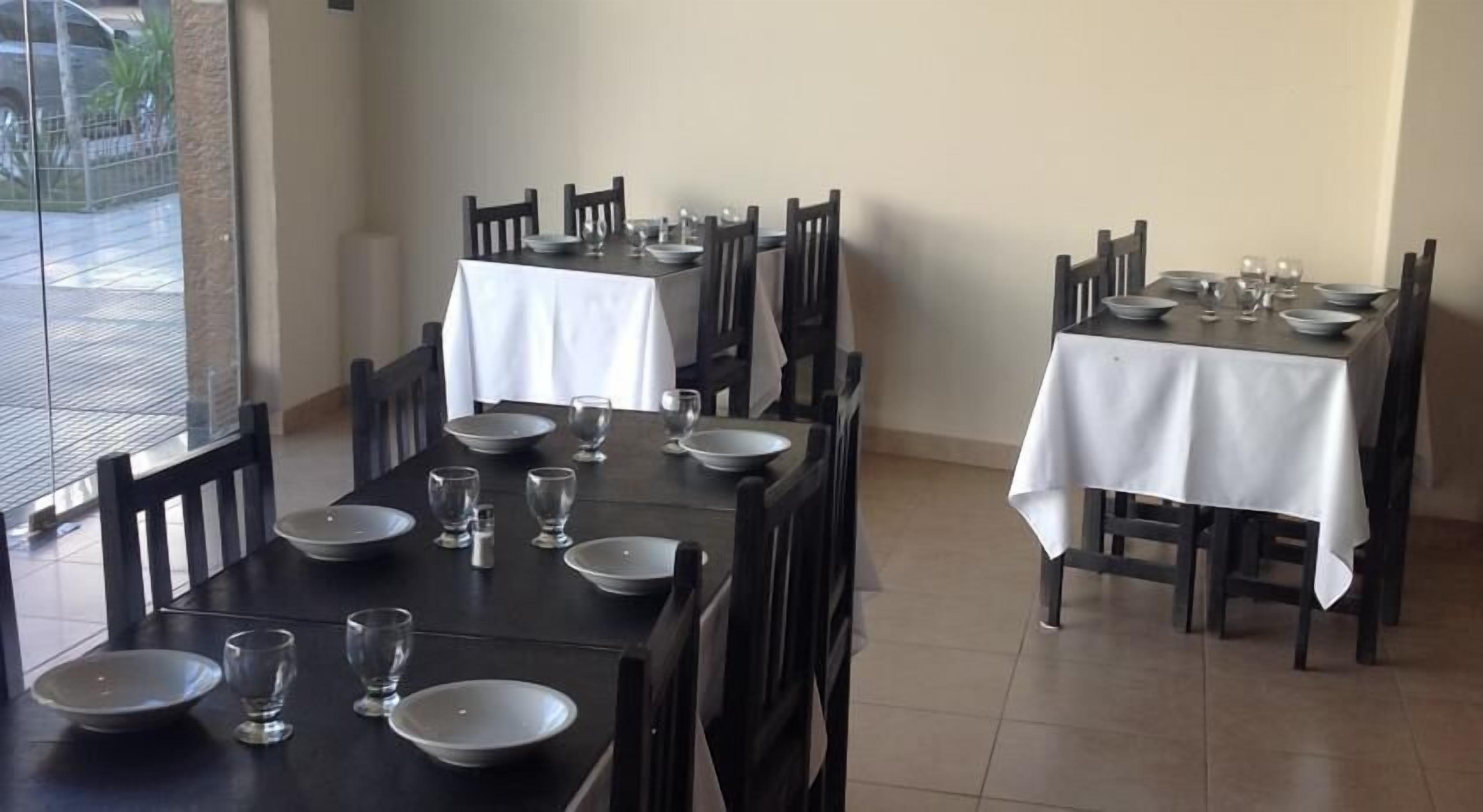 A restaurant with two tables set for dining, each with chairs, plates, and glasses.