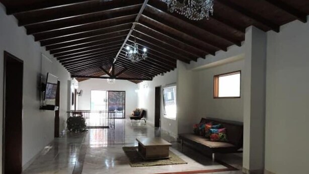 A spacious living area with a high ceiling, a sofa, a coffee table, and a TV mounted on the wall. - Hotel Porton Colonial (Medellín)