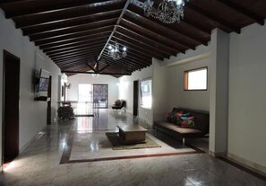Un salón comedor amplio con techo alto, un sofá, una mesa de centro y un televisor montado en la pared.
