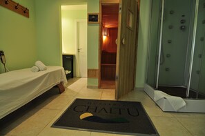 A hotel room with a bed, a shower, and a door leading to a wooden closet.