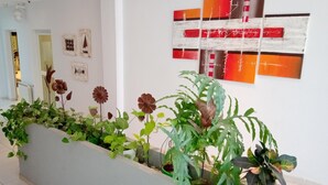 A hallway with a planter filled with various plants and flowers. There are abstract paintings on the wall.