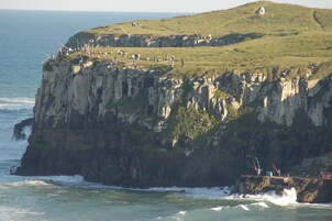 Un acantilado costero con un pequeño edificio en la cima, con vistas al mar.