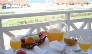 A table with a fruit basket, a pitcher of juice, and two glasses of orange juice. - Solar Dom Kido Pousada (Torres)