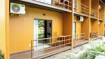 A building with a yellow exterior, a wooden balcony, and a door leading to an interior space.