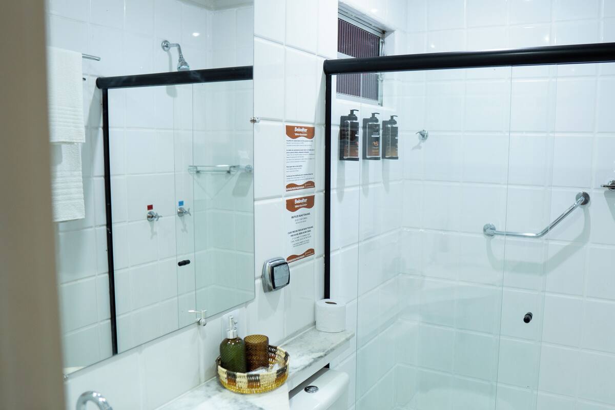 A modern bathroom with a glass shower enclosure, a toilet, a sink with a marble countertop, and a mirror.
