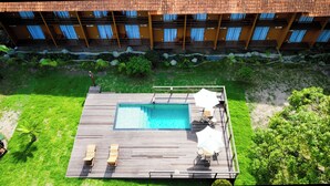 A hotel with a rooftop pool area, including a pool, lounge chairs, and umbrellas.