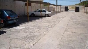 A parking area with two cars, a white sedan and a blue hatchback, parked under a covered structure. - Hotel La Argentina (San Bernardo del Tuyú)