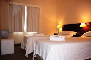 A hotel room with two beds, a desk, and a window with curtains. - Horizonte Hotel (Mar del Plata)