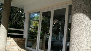 A hotel entrance with a glass door and a stone pillar. - Hotel Crismalu (San Martín de los Andes)
