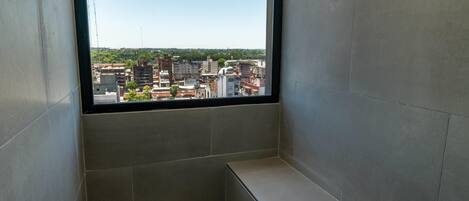 Una habitación con un ventanal grande, paredes con azulejos y un banco.