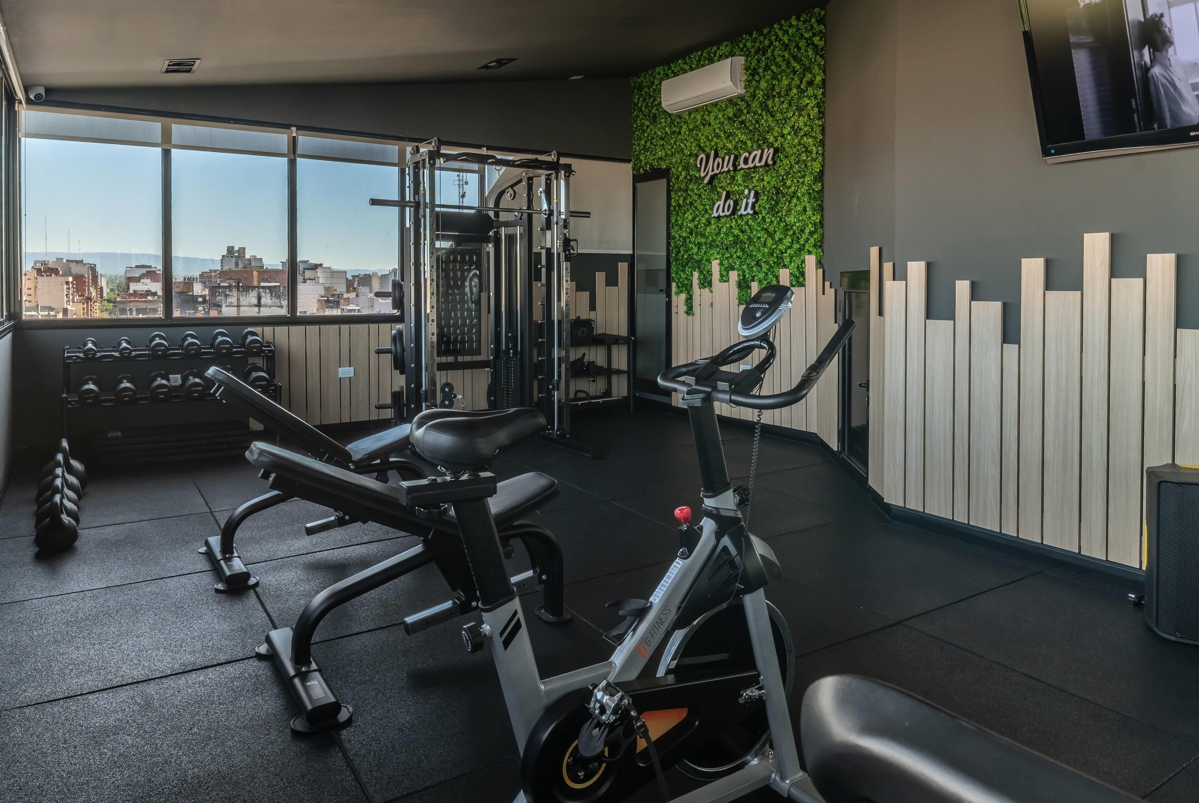 A gym with exercise equipment, a wall-mounted TV, and a motivational quote.