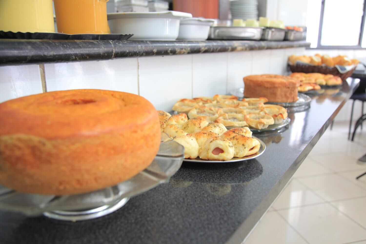 Een buffet met diverse gebakken producten, waaronder een grote ronde taart en verschillende kleine gebakjes.