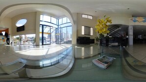 Eine großzügige Lobby mit einem gewölbten Glasboden, großen Fenstern und einer Treppe.