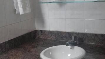 Een badkamer met een wit wastafelmeubel, een granieten aanrechtblad en een handdoekhouder.