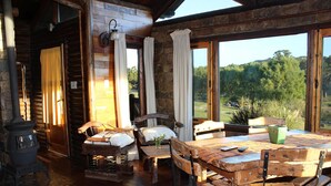 A rustic wooden interior with a large table, chairs, a fireplace, and a view of the outdoors. - Posada El Molino (Tandil)