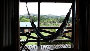 A hammock on a wooden deck with a view of a green landscape and hills. - Posada El Molino (Tandil)