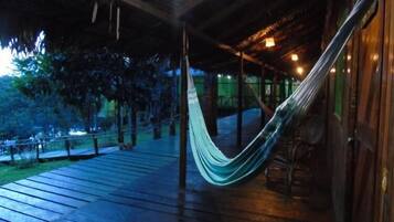 Relax in a hammock suspended between two posts on this deck, surrounded by a low fence and wooden railing.
