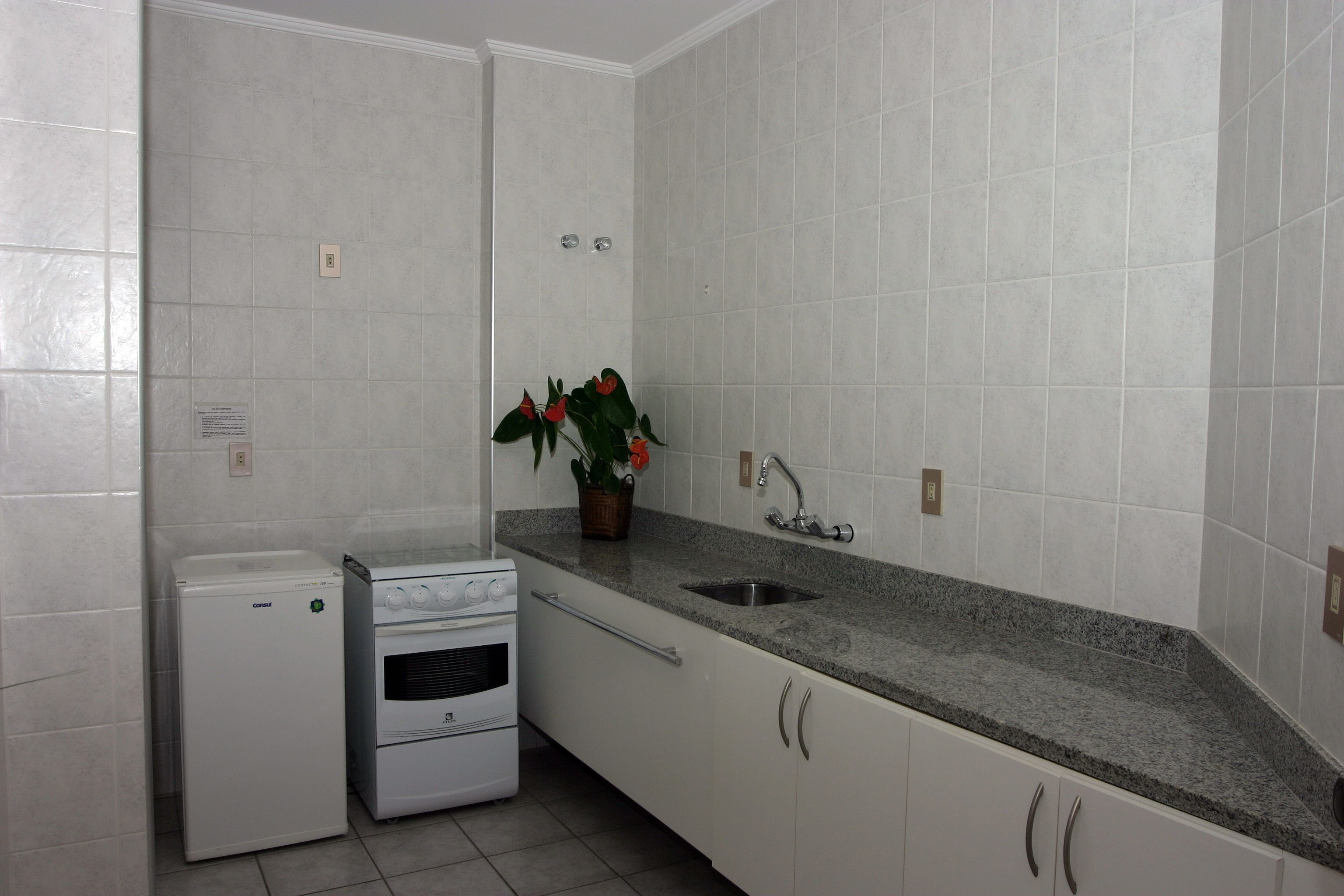 Una cocina con armarios blancos, encimera de granito, horno empotrado y un lavamanos.