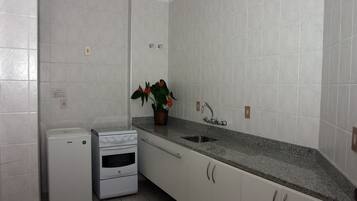 Una cocina con armarios blancos, encimera de granito, horno empotrado y un lavamanos.