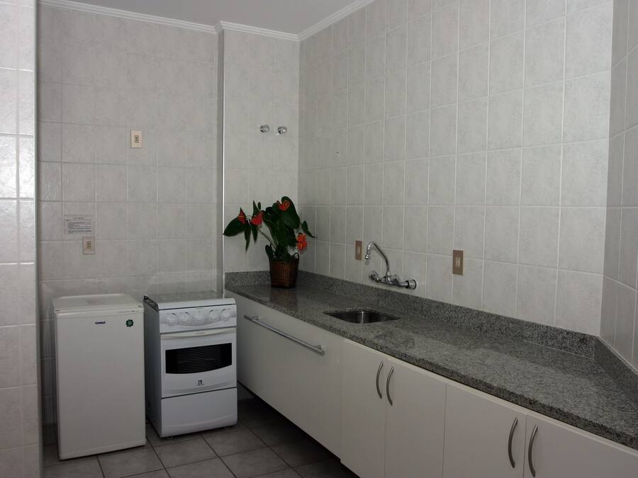 Una cocina con armarios blancos, encimera de granito, horno empotrado y un lavamanos.