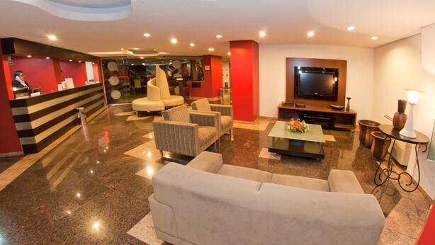 Un vestíbulo moderno con mostrador de recepción, zona de estar y televisor de pantalla plana.
