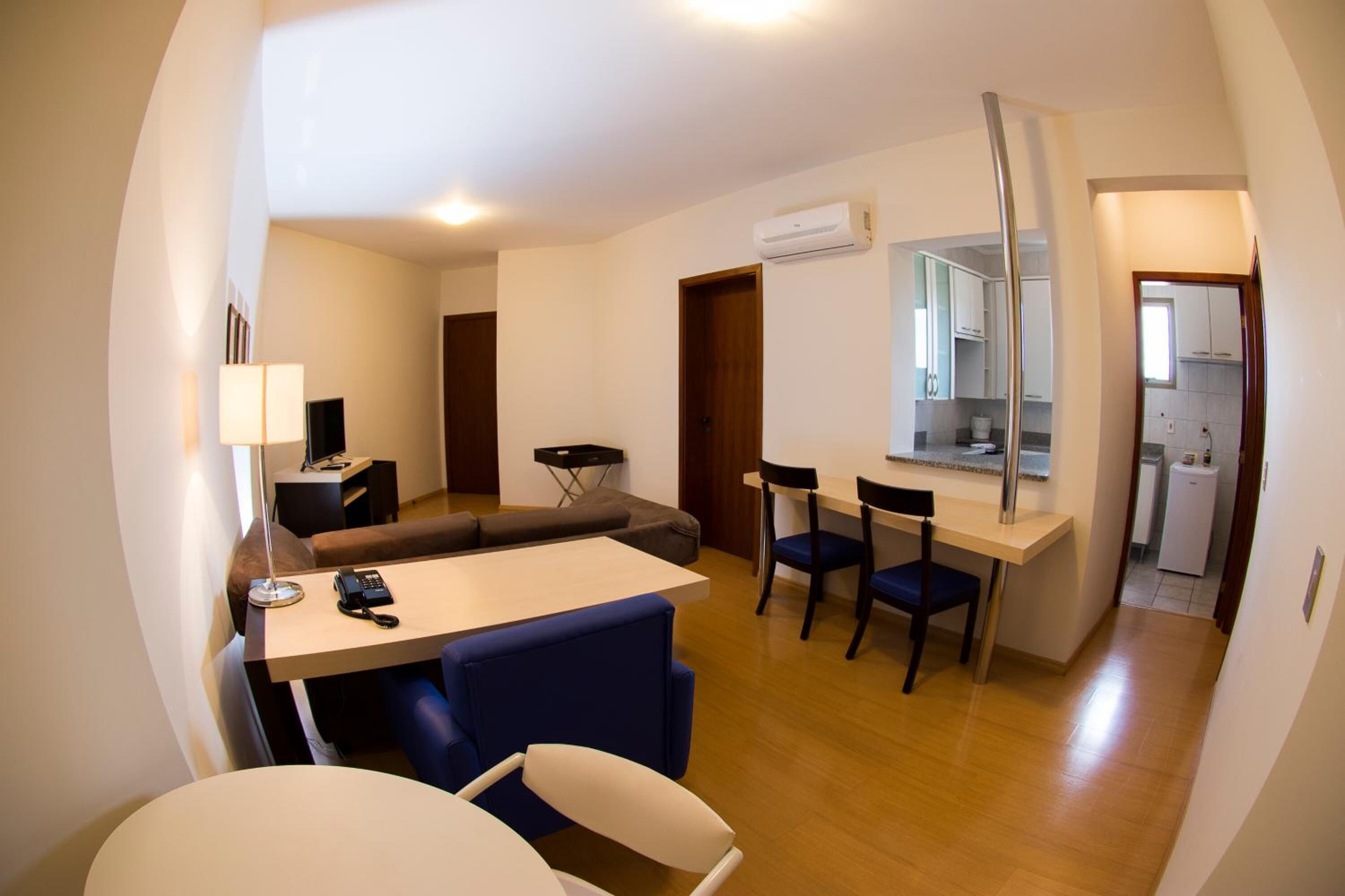 A compact living space with a dining area, a sofa, a small kitchen, and a bathroom visible through an open door.